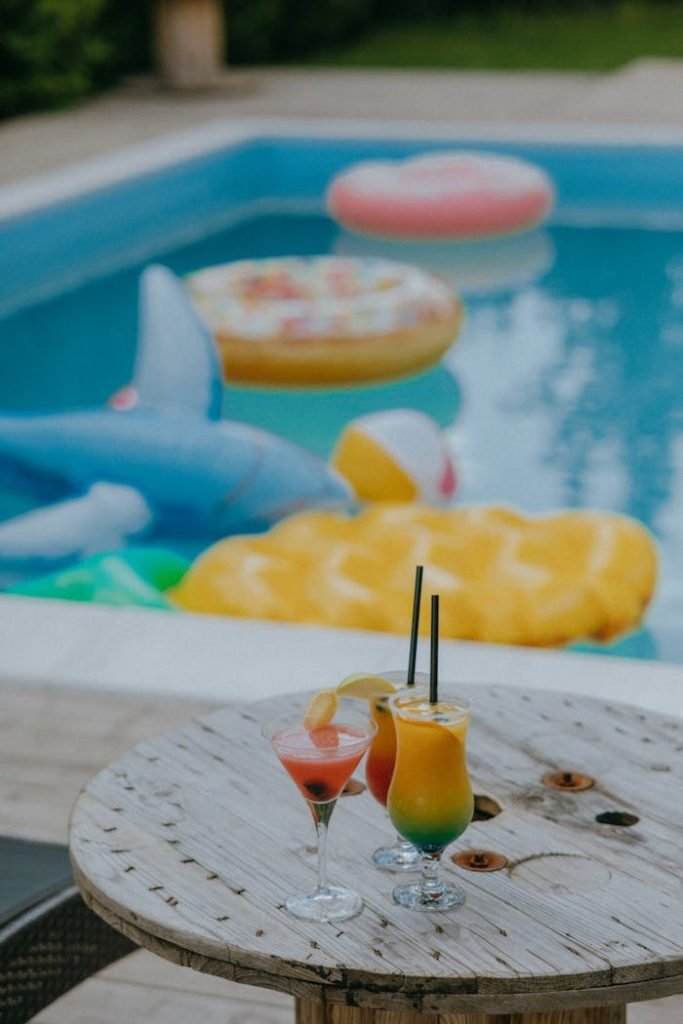 Colorful cocktails by the pool with fun inflatable shapes creating a tropical vibe.
